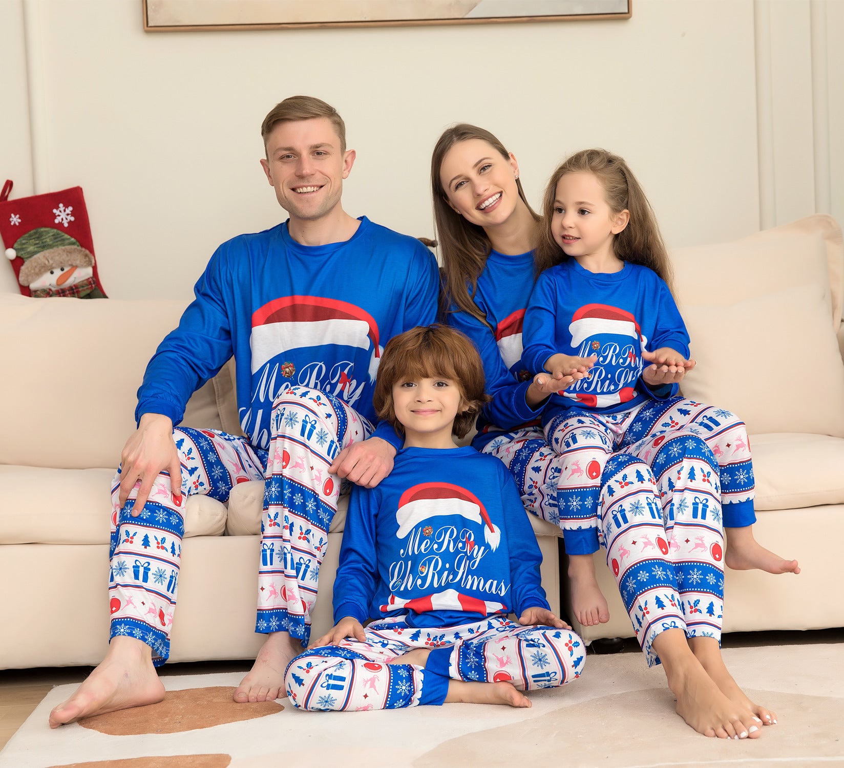 Family of four wearing matching blue Christmas pajamas with red and white accents.