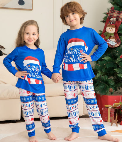 Two children wearing matching blue Christmas pajamas with red and white accents in a living room.