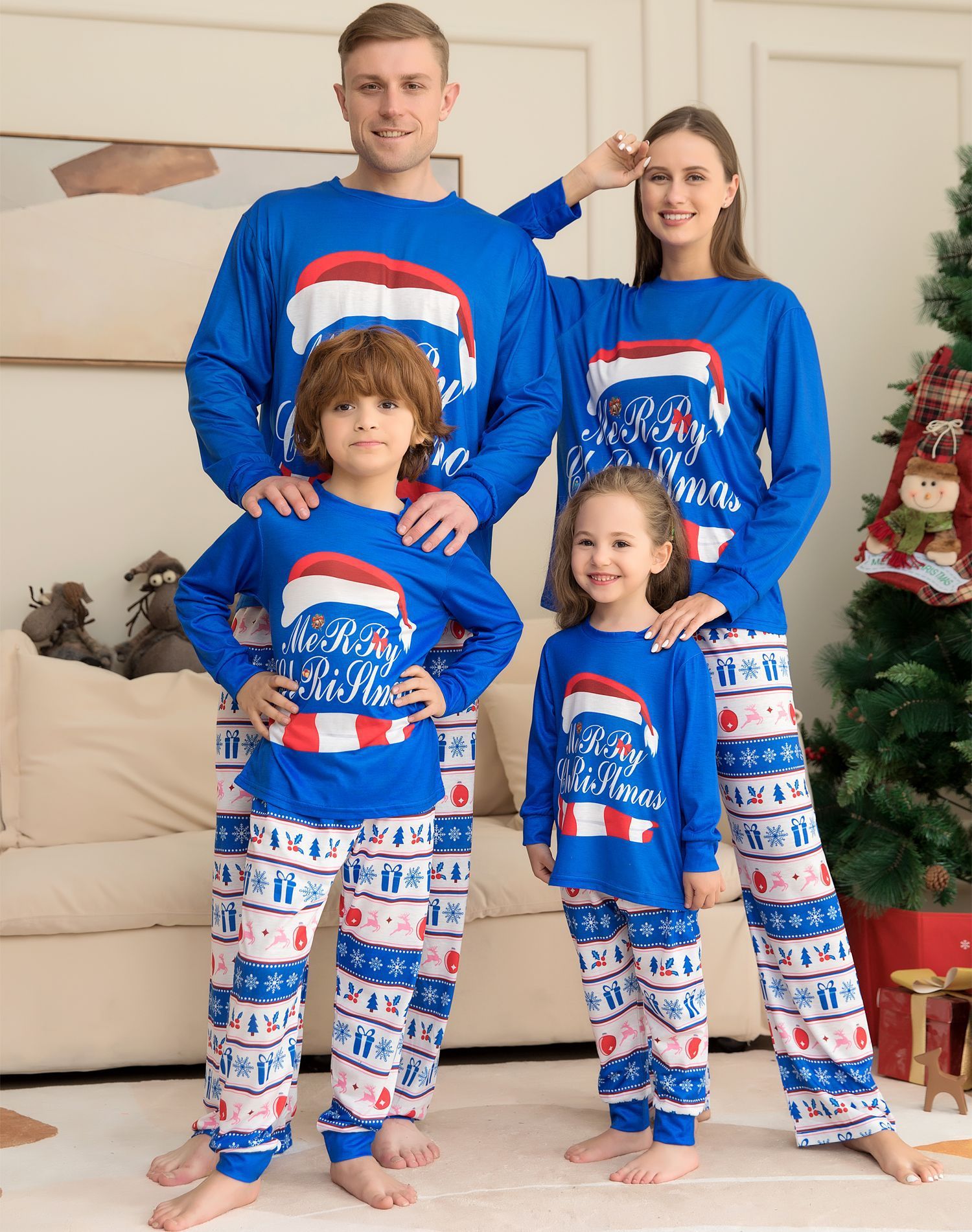 Family wearing matching blue Christmas pajamas with festive designs in a living room.