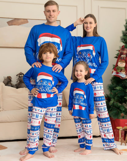 Family wearing matching blue Christmas pajamas with festive designs in a living room.